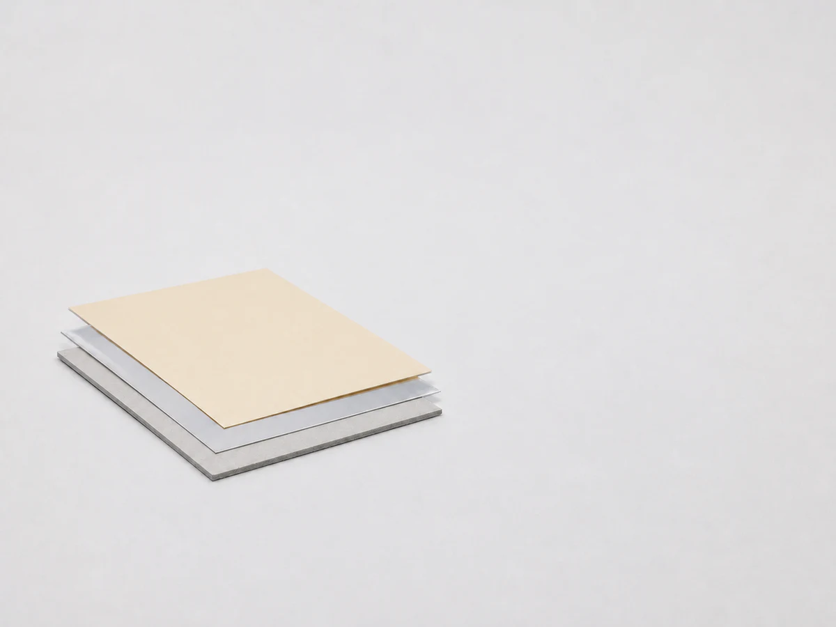 Illustrative unbranded paperboard, film and foil-like material study for a transfer-adhesive discussion.